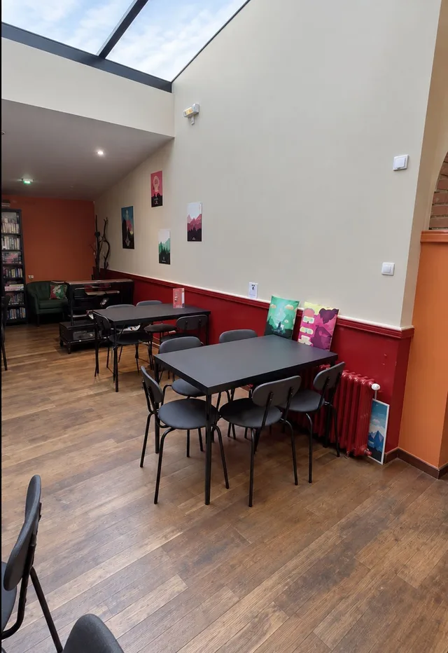La salle sous verrière du Repaire du Phoenix à Montauban, ses tables de jeu et son parquet